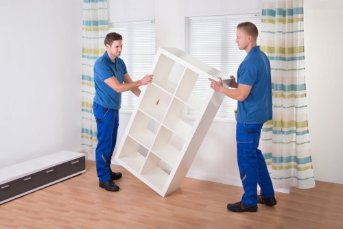Professional movers carrying furniture through a narrow London street